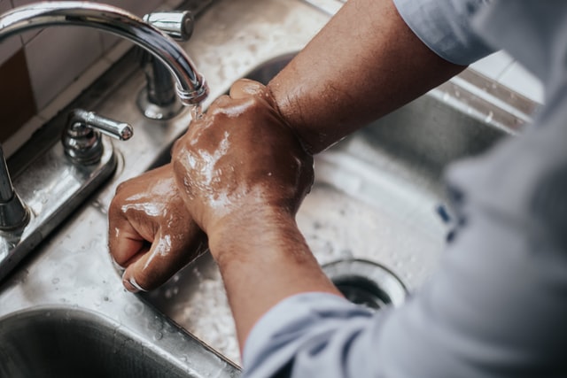 Jemand wäscht sich die Hände unter einem Wasserhahn