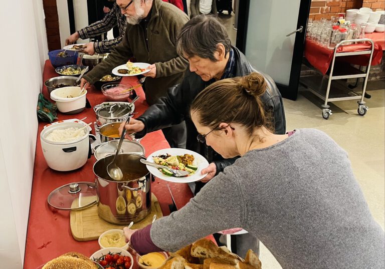 Menschen stehen an einem Buffet.