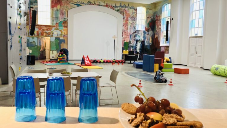 Gottesdienstsaal mit Spielgeräten, im Vordergrund Getränke und Snacks auf einer Bar.