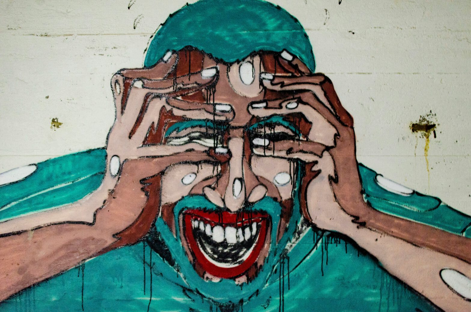 Mural eines schmerzerfüllten Gesichts, das sich auf beide Arme stützt, die Hände an den Schläfen.