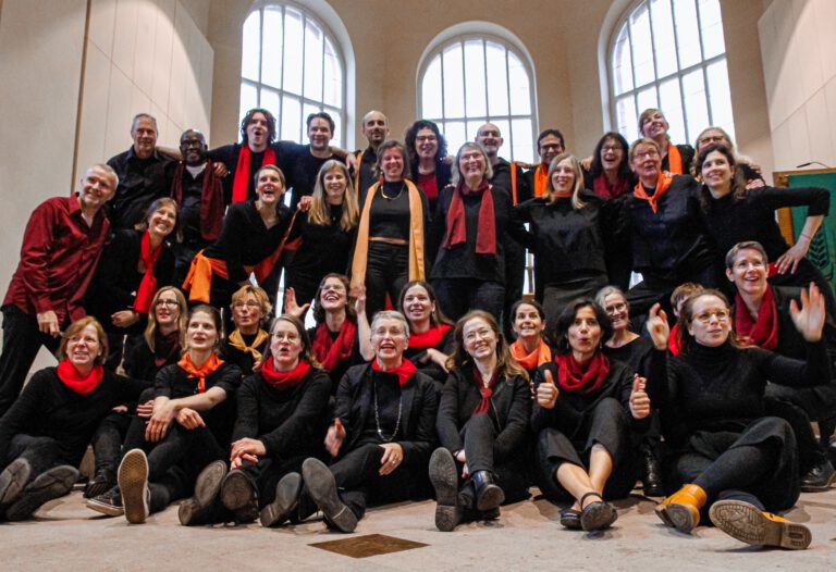Gruppenbild Chor Unifying Voices in schwarzer Kleidung mit roten Halstüchern